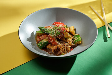 Oriental wok noodles with vegetables and sauce in a plate in bright backgrounds. Selective focus, hard shadows