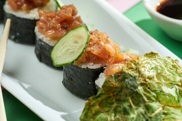 Sushi roll with tuna and cucumber in a plate of bright backgrounds. Selective focus, hard shadows