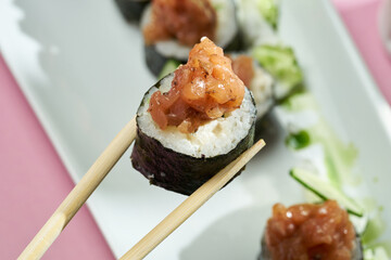 Sushi roll with tuna and cucumber in a plate of bright backgrounds. Selective focus, hard shadows