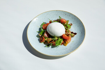 Salad with burrata cheese and cherry tomatoes on white wooden background