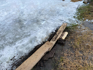 Fototapeta premium Wooden boards were used to pull the car out of the mud to create traction. Early spring and wet muddy meadow. Offroad.