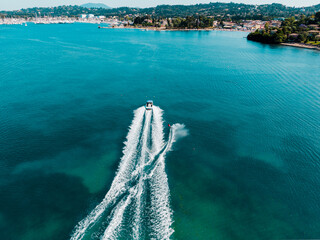 Aerial photo of extreme power boat water-sports cruising in high speed in deep blue corfu island...