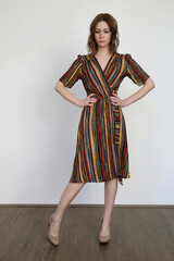 Woman in funky multicolor striped wrap midi dress. Studio shot.