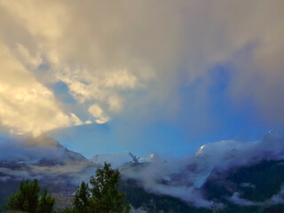 The Mont Blanc Range at dusk, with the sun reflecting from the highest top and dark clouds. As seen from Chamonix, Haute Savoie, France
