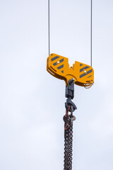 Crane hoisting block with hook on steel chain on the steel rope. Loading\unloading of building materials on construction building site.  Development.