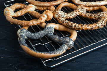 Fresh prepared homemade soft pretzels. Different types of baked bagels with seeds on a black background.