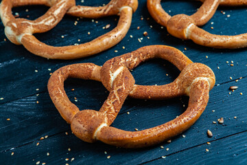 Fresh prepared homemade soft pretzels. Different types of baked bagels with seeds on a black background.