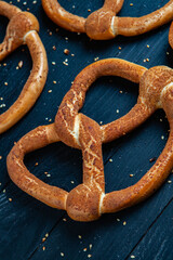 Fresh prepared homemade soft pretzels. Different types of baked bagels with seeds on a black background.
