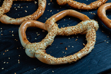 Fresh prepared homemade soft pretzels. Different types of baked bagels with seeds on a black background.