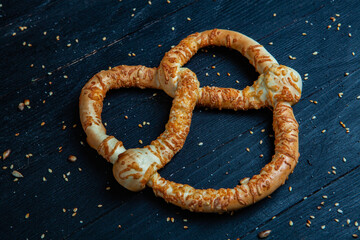 Fresh prepared homemade soft pretzels. Different types of baked bagels with seeds on a black background.