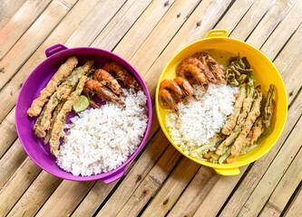 bowl of rice with side dish cucumbers, fried prawns and crispy fried beans.