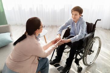 Psychotherapy consultation. Counselor offering help and support to disabled teen boy in wheelchair...