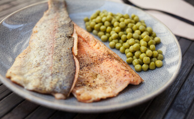 Fried trout fillets served with green peas