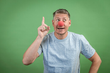 man with red clown nose and grey shirt in front of green background