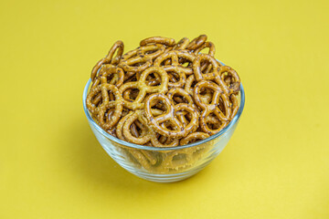 Salted mini pretzels in a deep glass bowl on a yellow background