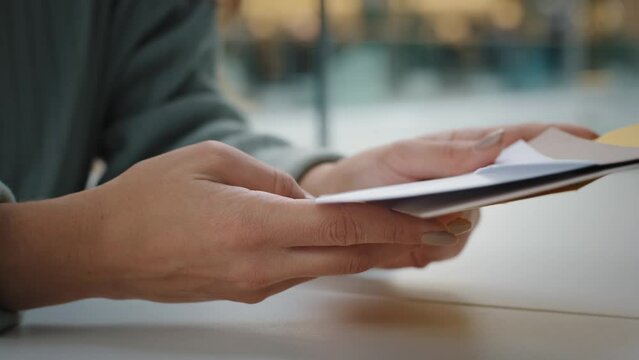 Close-up female hands holds envelopes letters correspondence receive alerts from bank account. Unrecognizable woman sitting at table checking mail holding papers documents got invitation loan approved