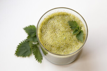 Healthy nettle herb smoothie on the white background decorated with fresh nettle leaves