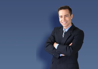 Smiling young businessman with arms crossed in studio background