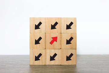 Unique, Difference thinking concept. woodblock cubes with arrow. Red arrow facing the opposite direction from black arrows.