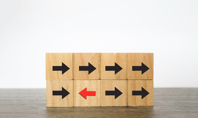 Unique, Difference thinking concept. woodblock cubes with arrow. Red arrow facing the opposite direction from black arrows.