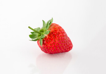 Fresh organic strawberries on a white reflective surface. Close up shot.