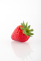 Fresh organic strawberries on a white reflective surface. Close up shot.