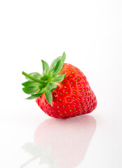 Fresh organic strawberries on a white reflective surface. Close up shot.