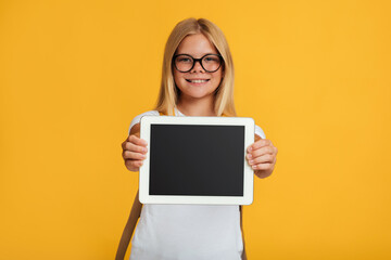 Happy teenager blonde lady schoolgirl in glasses shows tablet with blank screen, recommends new app