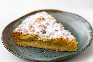 Piece of pie in ceramic plate on white wooden  background.