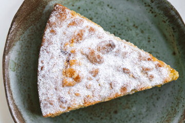 Piece of pie in ceramic plate on white wooden  background.
