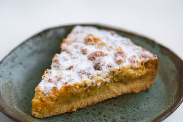 Piece of pie in ceramic plate on white wooden  background.
