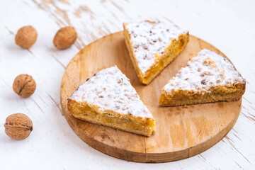 Sliced homemade apple and nuts cake on wooden background