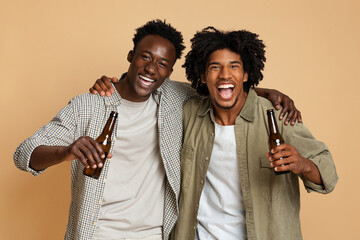 Portrait Of Two Happy Black Friends Embracing And Holding Bottles With Beer