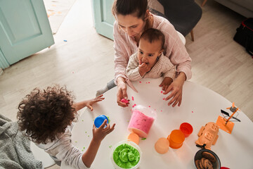 Cute little boys playing with kinetic sand at home near their mother