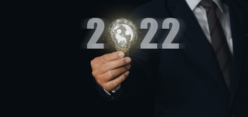 Businessman holding light bulb with virtual Global Internet connection 2022 and metaverse.