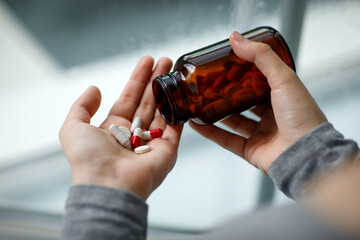 Cropped despair millennial caucasian woman puts pills from can on her hand for committing suicide