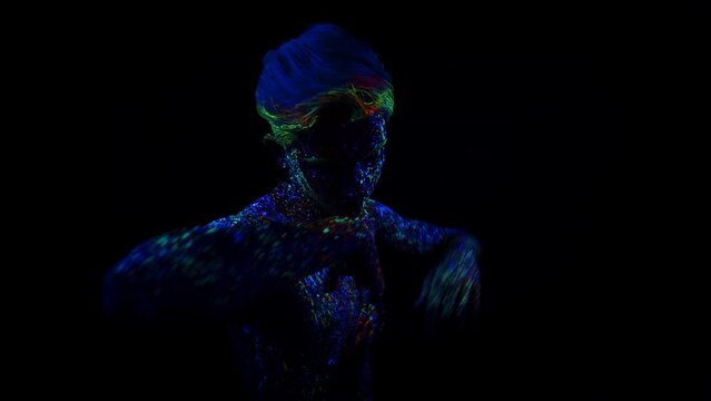 Young man painted with fluorescent paint dances smoothly. Man moves her hands beautifully in the dance. Moving in different directions. Front view. Body art concept