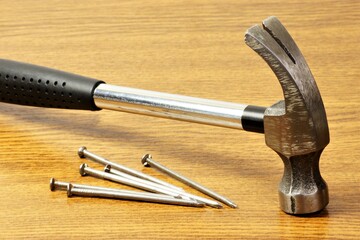 A metal hammer, a construction locksmith tool for hammering fastening nails. Isolated on a wooden background.