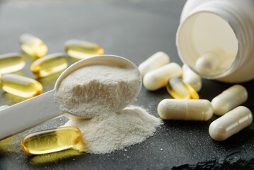 sports supplements close-up with selective focus. Measuring spoon with creatine, omega-3 capsules...
