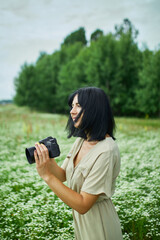 Female photographer take photo outdoors on flower field landscape holding a camera