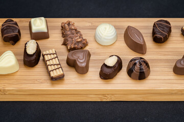 Variety of chocolate candies served on a wooden board for valentines day