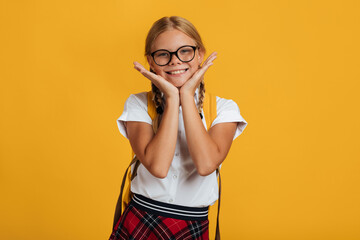 Happy smiling caucasian teen girl student in glasses with pigtails and backpack posing at camera