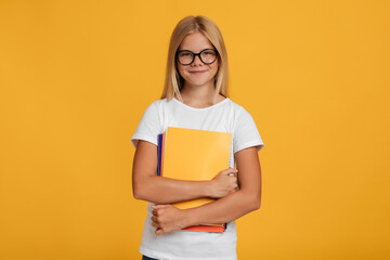 Happy smart caucasian teen girl pupil in white t-shirt and glasses hold books, notebooks