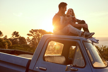 Hilltop romance at sunset. Shot of an affectionate young couple on a roadtrip.