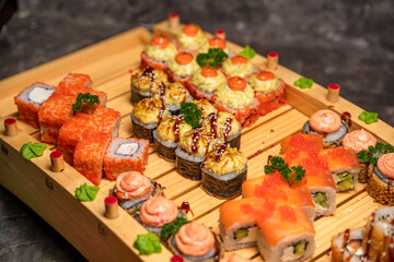 large set of Japanese rolls and sushi on a black background, wooden tray