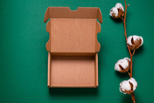 Brown cardboard box on green background with cotton flower