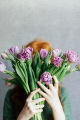 The girl hid her face behind a bouquet of tulips
