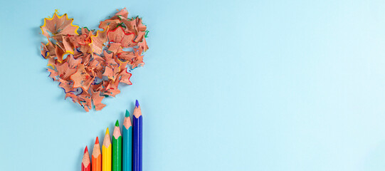 banner with Sharpened colored pencils and heart-shaped pencil shavings on pastel blue color. Rainbow or LGBT pencils. Decoration for St. Valentine's Day. Top view - Powered by Adobe