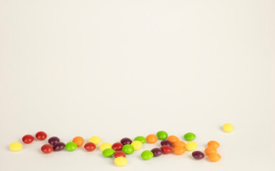 Multi-colored round candies on a light background with copy space. Conceptual background. Sweet candies of different colors on a white table.