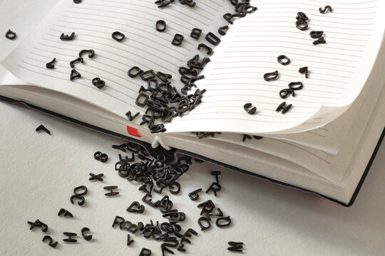 black small latin letters on the blank pages of the book and around, the concept of learning a foreign language, learning to read, literary experiments